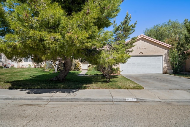 obstructed view of property with a garage, concrete driveway, a tile roof, a front lawn, and stucco siding