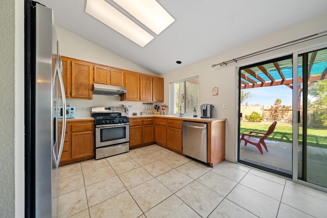 kitchen featuring light tile patterned floors, lofted ceiling, appliances with stainless steel finishes, light countertops, and under cabinet range hood