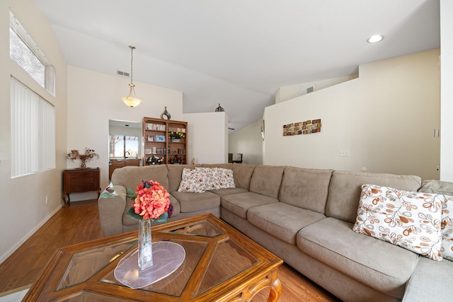 living area with vaulted ceiling, wood finished floors, and visible vents