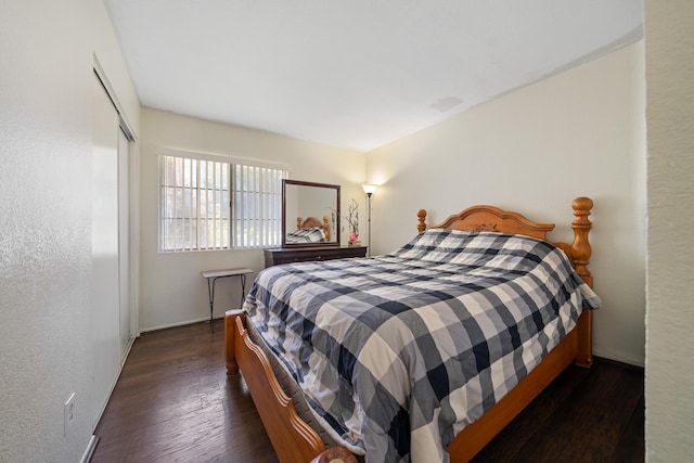 bedroom with dark wood-style floors, a closet, and a textured wall