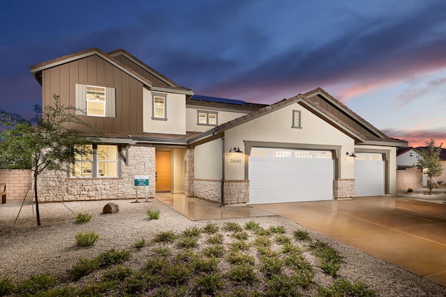 view of front of property with stone siding, solar panels, concrete driveway, and a garage