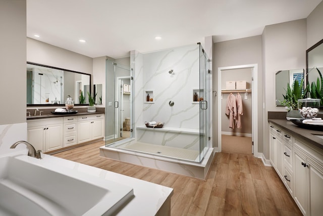 full bathroom featuring vanity, recessed lighting, wood finished floors, and a marble finish shower