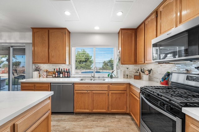 kitchen with sink, backsplash, light stone countertops, and stainless steel appliances