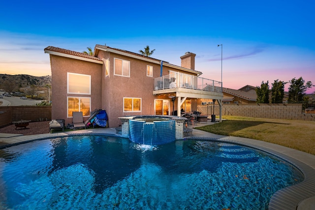 pool at dusk featuring an in ground hot tub, a patio area, and a lawn