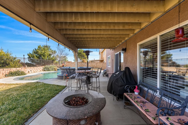 view of patio / terrace with grilling area, a fenced in pool, and a fire pit