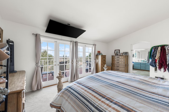 bedroom featuring lofted ceiling, connected bathroom, access to outside, and light colored carpet