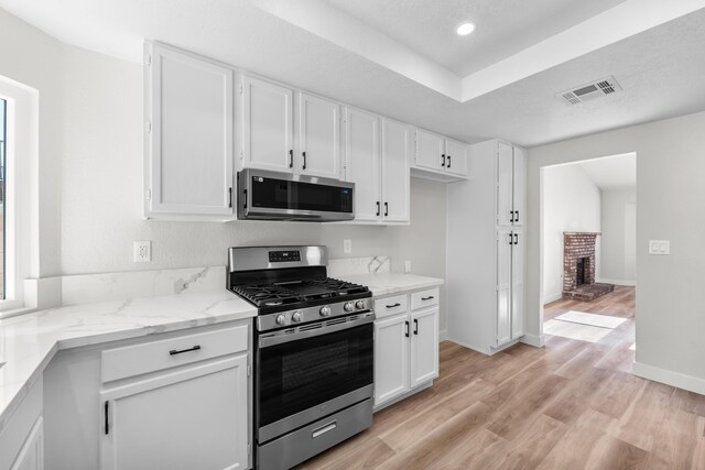 1032 Glenn Ct, Lancaster, CA 93535 - kitchen with stainless steel appliances, white cabinetry, light wood-type flooring, light stone countertops, and recessed lighting