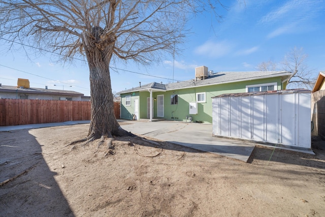 back of property featuring fence, central AC unit, a patio, an outdoor structure, and a shed