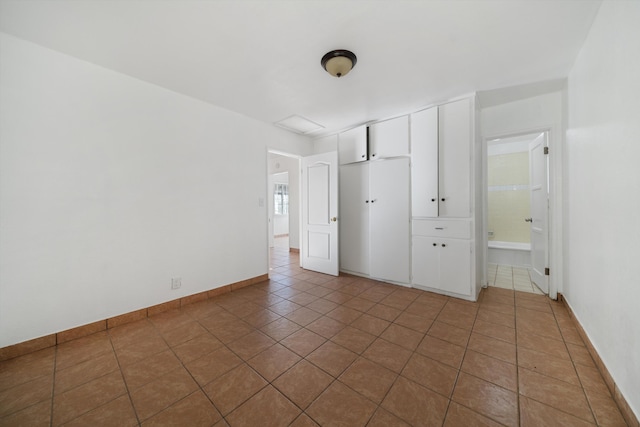 unfurnished bedroom with tile patterned flooring and baseboards