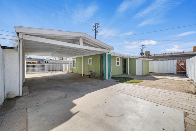 exterior space featuring stucco siding, fence, driveway, a gate, and an attached carport