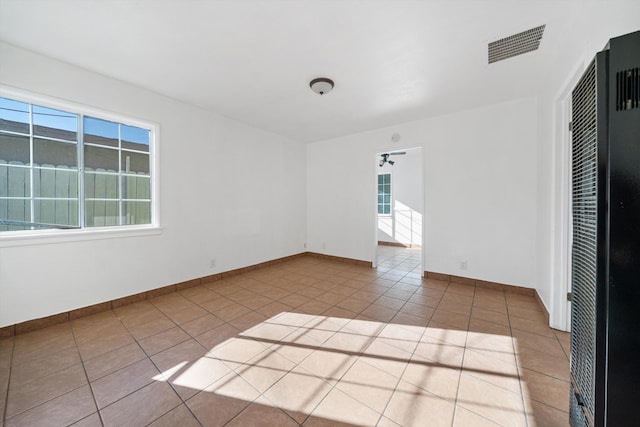 empty room with tile patterned floors, a heating unit, baseboards, and visible vents