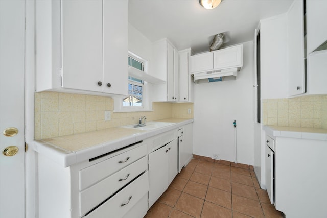kitchen featuring tile counters, white cabinetry, tasteful backsplash, and a sink