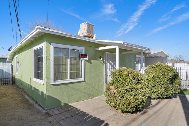 view of side of property with stucco siding and fence