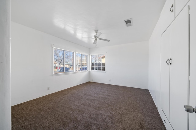 carpeted empty room featuring visible vents and a ceiling fan