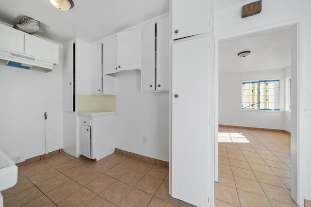 kitchen with light tile patterned flooring, white cabinets, light countertops, and decorative backsplash