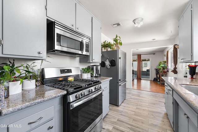 44049 Elm Ave, Lancaster, CA 93534 - kitchen featuring appliances with stainless steel finishes, light wood-style floors, and light stone countertops