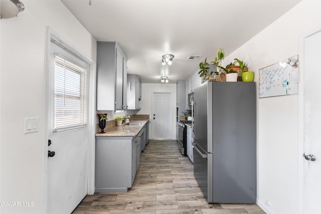 44049 Elm Ave, Lancaster, CA 93534 - kitchen featuring stainless steel appliances, gray cabinets, light wood-style flooring, and light countertops