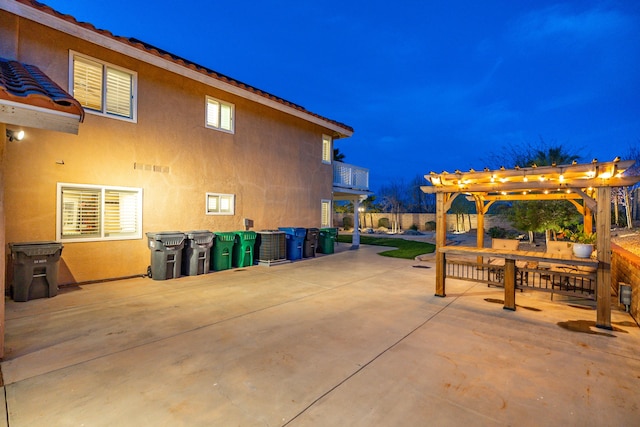 view of side of property with a patio area, stucco siding, a balcony, and a pergola