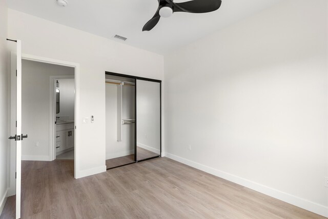 unfurnished bedroom featuring baseboards, visible vents, light wood finished floors, ceiling fan, and a closet