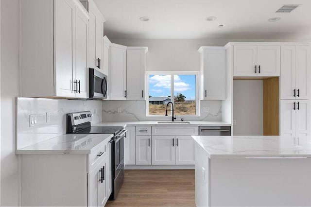 kitchen featuring visible vents, a sink, white cabinetry, appliances with stainless steel finishes, and decorative backsplash