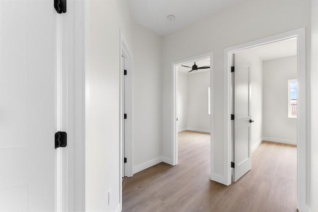 corridor with baseboards and light wood-style flooring