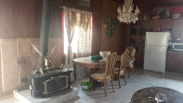 dining area with wood walls, a wood stove, and a chandelier