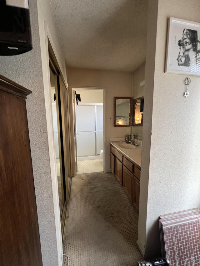 1607 E Newgrove St, Lancaster, CA 93535 - bathroom featuring a textured ceiling, vanity, toilet, a shower with door, and a textured wall