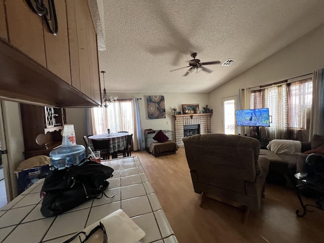1607 E Newgrove St, Lancaster, CA 93535 - living room with a ceiling fan, a textured ceiling, light wood finished floors, a fireplace, and vaulted ceiling