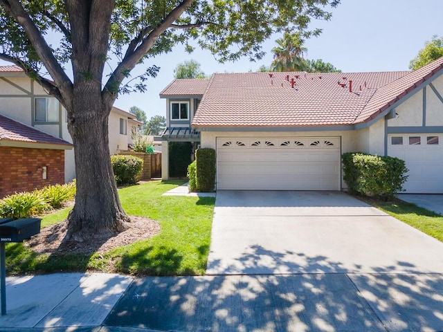 view of front of property with a garage, concrete driveway, a tile roof, a front lawn, and stucco siding