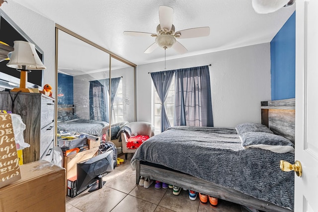 tiled bedroom with ceiling fan, a textured ceiling, and a closet