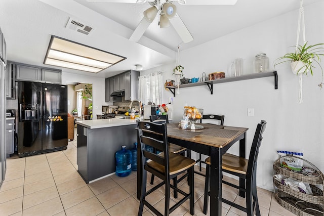 kitchen featuring kitchen peninsula, gray cabinets, black fridge with ice dispenser, and light tile patterned floors