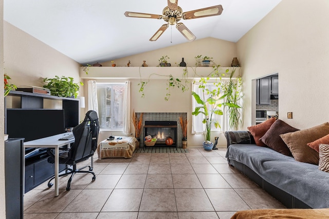 interior space featuring ceiling fan, a fireplace, light tile patterned floors, and lofted ceiling