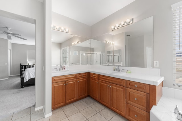 ensuite bathroom with ceiling fan, double vanity, tile patterned floors, and baseboards