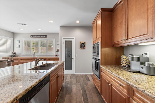 kitchen featuring a sink, stainless steel appliances, dark wood-type flooring, light stone countertops, and brown cabinetry