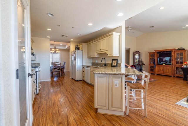 kitchen with kitchen peninsula, appliances with stainless steel finishes, light wood-type flooring, a kitchen breakfast bar, and sink