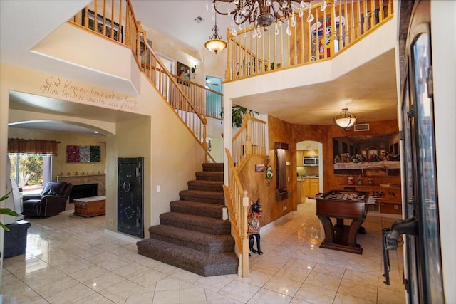41904 Tucson Ct, Palmdale, CA 93551 - stairs featuring a fireplace, a high ceiling, arched walkways, marble finish flooring, and a chandelier