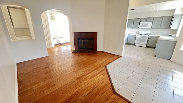 unfurnished living room with built in shelves, light wood-type flooring, and a brick fireplace