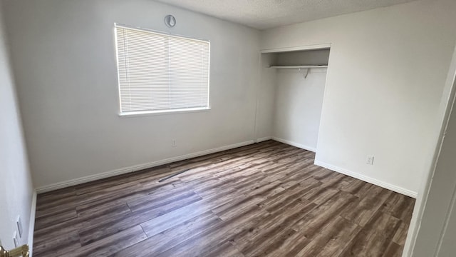 unfurnished bedroom featuring a textured ceiling, dark hardwood / wood-style floors, and a closet