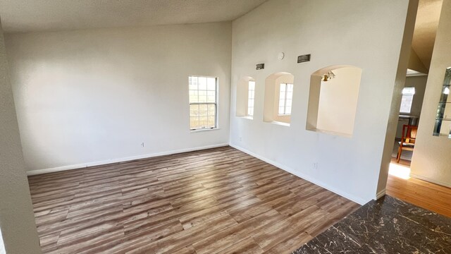 unfurnished room with hardwood / wood-style floors and high vaulted ceiling