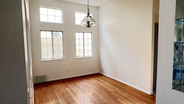 unfurnished dining area featuring light wood-type flooring and an inviting chandelier