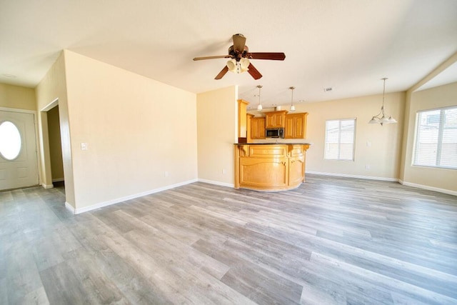 unfurnished living room with light wood-style flooring, baseboards, and ceiling fan