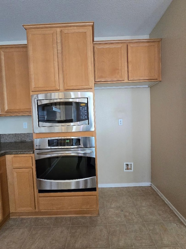 39294 Butler St, Palmdale, CA 93551 - kitchen featuring appliances with stainless steel finishes, dark countertops, baseboards, a textured ceiling, and tile patterned flooring