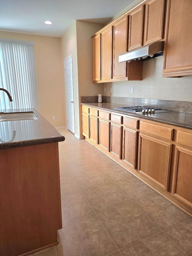 39294 Butler St, Palmdale, CA 93551 - kitchen with under cabinet range hood, a sink, dark stone counters, and stainless steel gas cooktop
