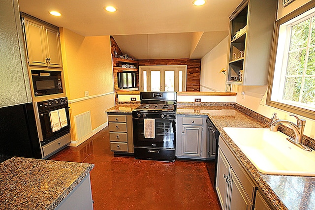 kitchen featuring a peninsula, plenty of natural light, black appliances, and a sink