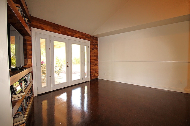 entryway with vaulted ceiling, wood walls, baseboards, and french doors