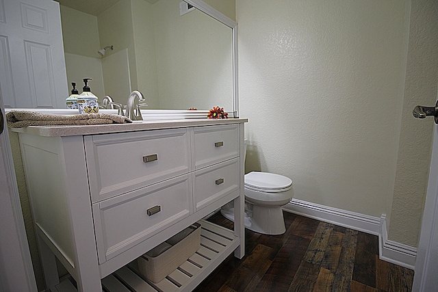 bathroom with baseboards, toilet, visible vents, vanity, and wood finished floors