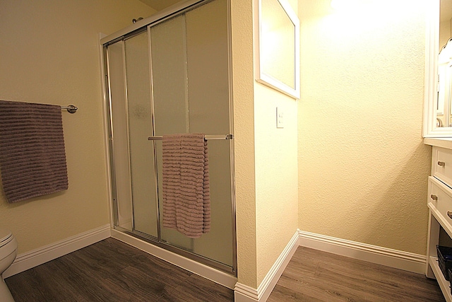 bathroom with vanity, baseboards, wood finished floors, and a shower stall