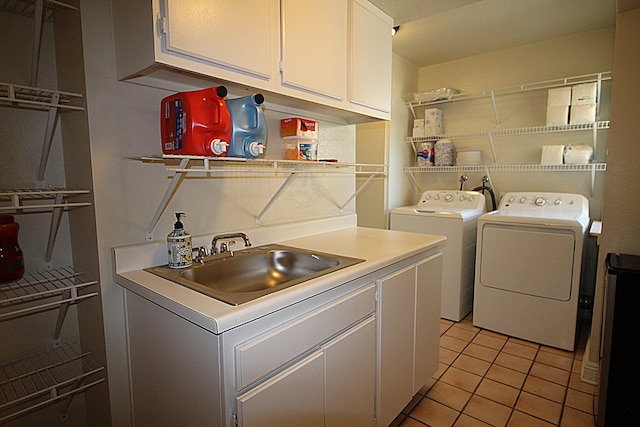 laundry area with washer and dryer, cabinet space, light tile patterned floors, and a sink