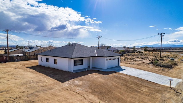 view of front of home with stucco siding, driveway, fence, roof with shingles, and an attached garage