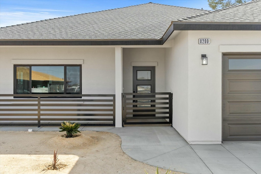 property entrance with roof with shingles and stucco siding